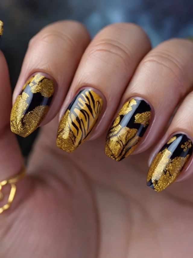 A woman's nails with gold and black tiger designs.