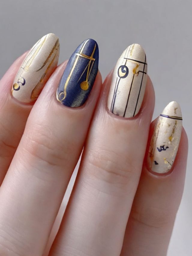 A woman's nails are decorated with gold and blue designs.