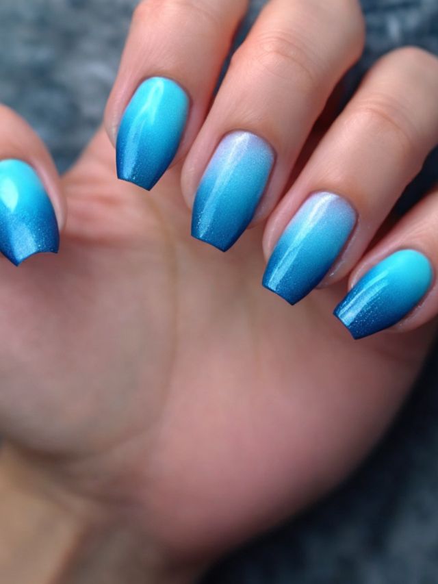 A woman's hand with blue and white ombre nails.