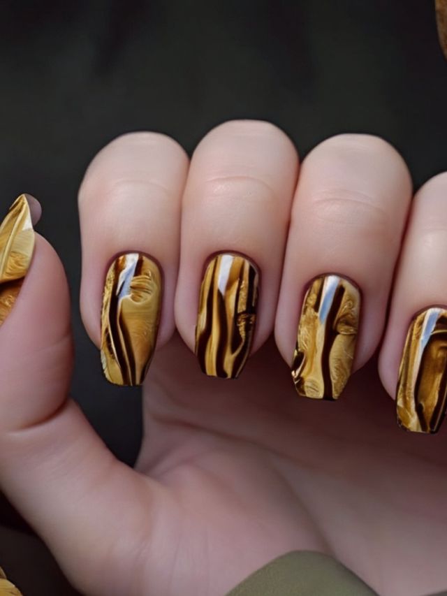A woman's nails with gold and black marble designs.