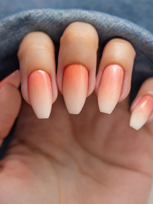 A person holding a pair of orange and white ombre nails.