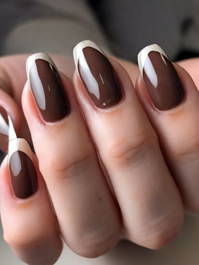 A woman's hand with brown and white manicured nails.
