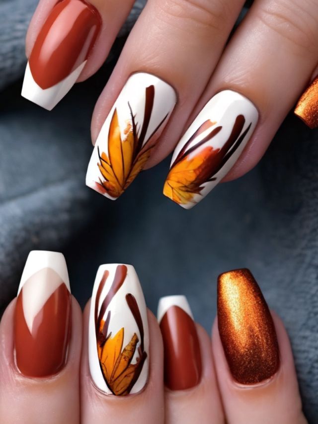 A woman's nails are decorated with orange and white leaves.