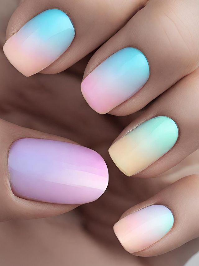 A woman's hand with pastel colored ombre nails.