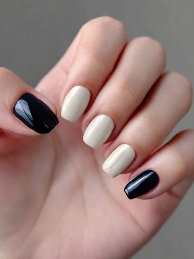 A woman's hand holding a black and white manicure.