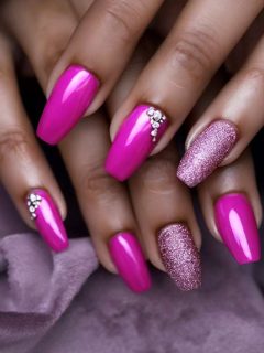 A woman's pink nails with glitter and diamantes.