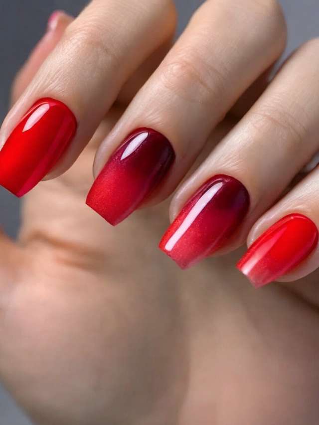 A woman's hand with red ombre nails.