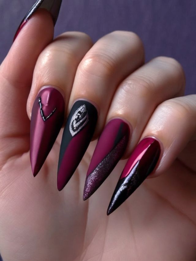 A woman's nails with burgundy and black designs, perfect for fall.