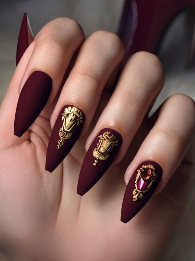 A woman with burgundy nails and gold fall designs.