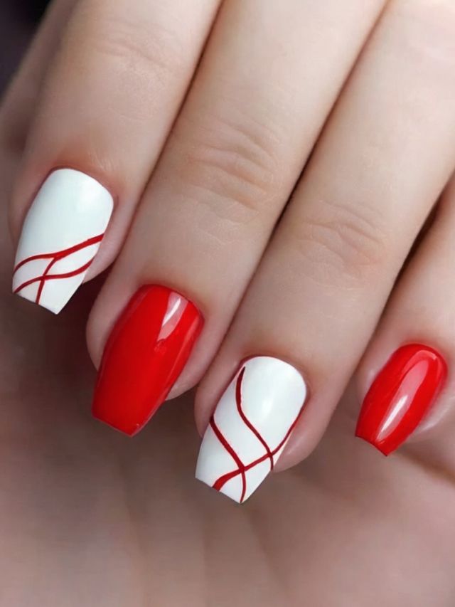 A woman's hand with red and white Nail Designs.
