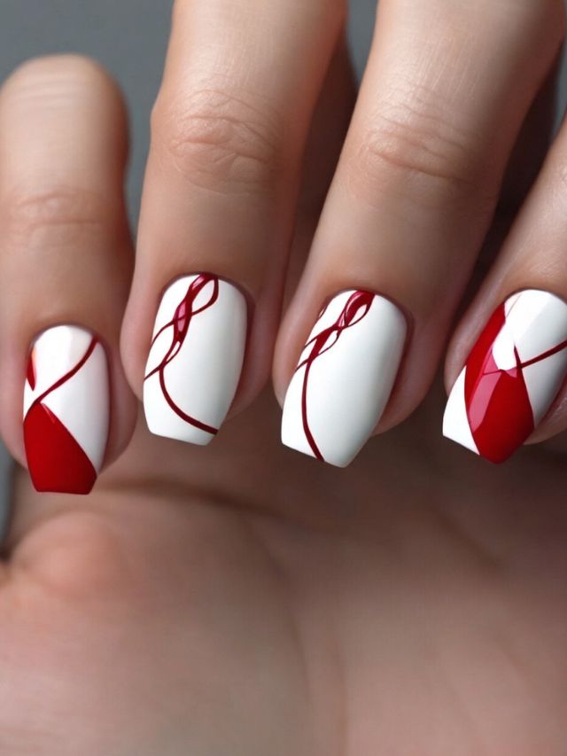 A woman's nails adorned with red and white nail designs.