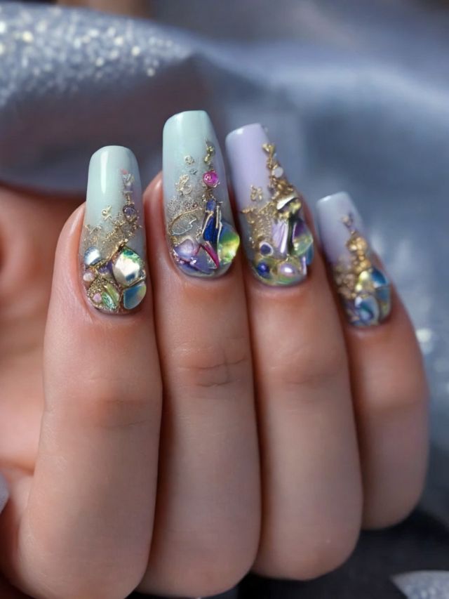 A woman's nails are decorated with gold and crystals.
