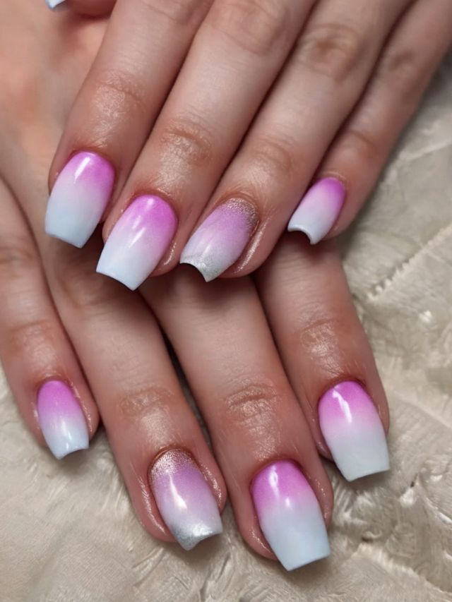 A woman's hands with pink and white ombre nails.