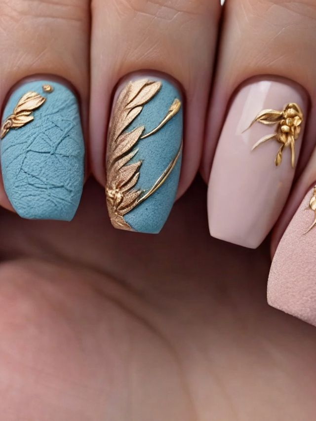A woman's nails are decorated with gold and blue leaves.