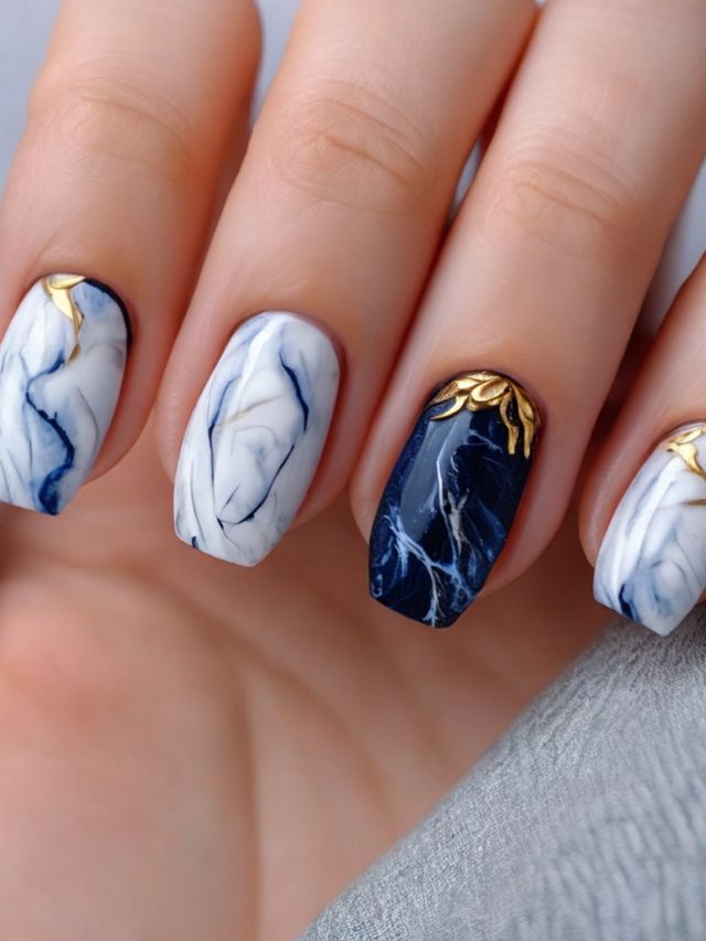 A woman's hand with marble nails and gold accents.
