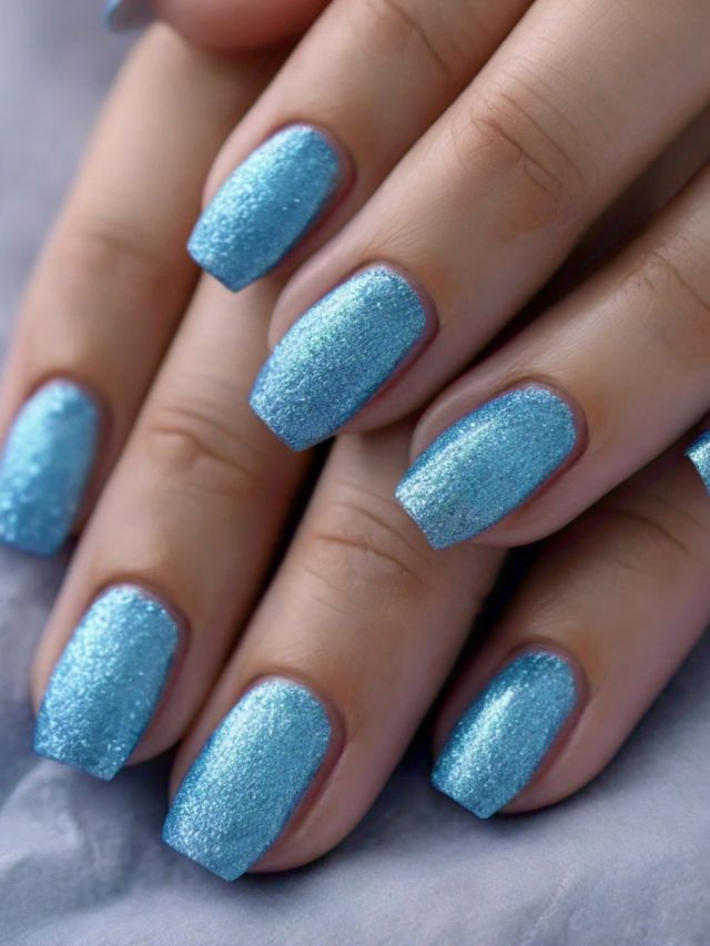 A woman's hands with cute blue glitter nails.