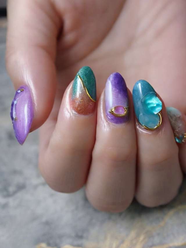 A woman's hand with purple, green, and blue nails.