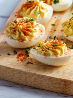 Deviled eggs on a wooden cutting board.