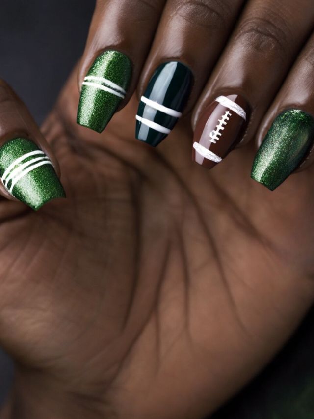 A woman with green and white Chiefs nail designs holding a football.