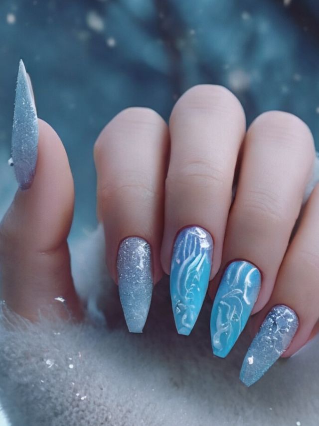 A woman holding a blue nail with snowflakes on it, showcasing the perfect January nail design.