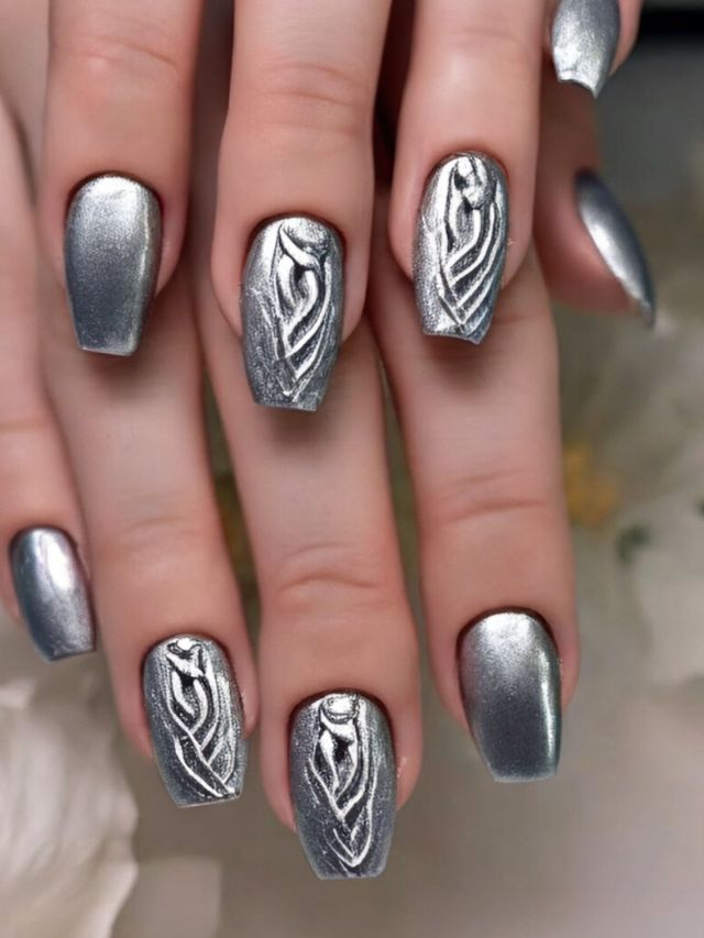 A woman's nails with silver designs on them.