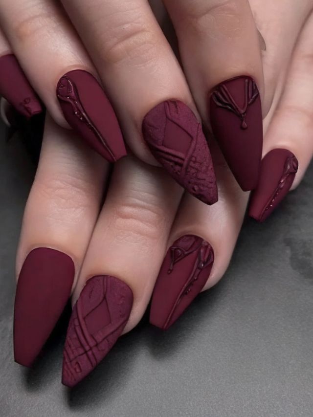 A woman's hands with burgundy nails showcasing cute fall toe nail designs.