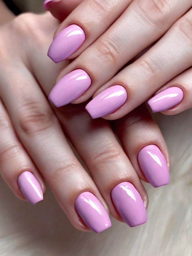A woman's hands with pink nail polish on them.