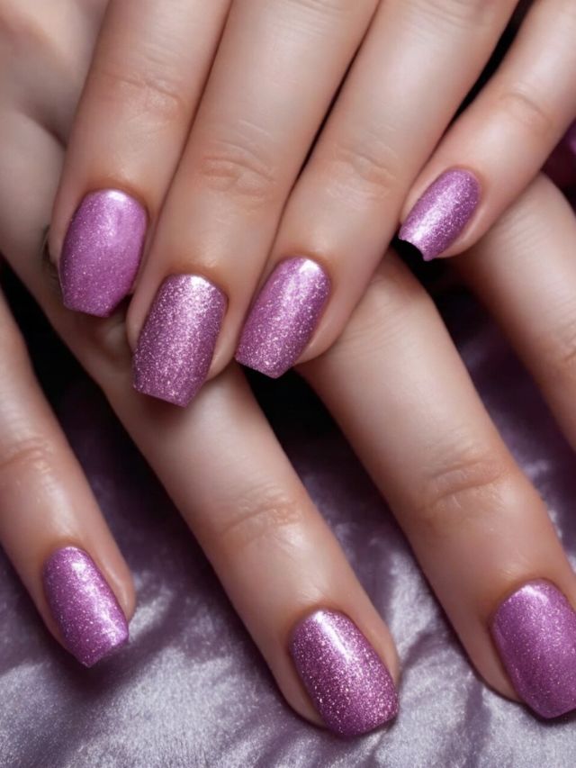 A woman's hands with purple nails on a purple background.