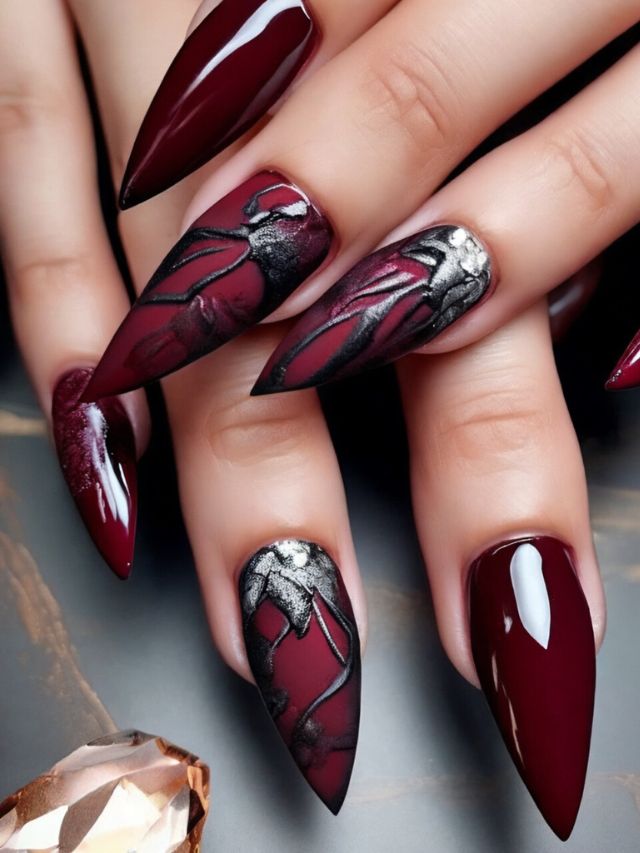 A woman's hands with burgundy nails and a diamond, showcasing an elegant fall nail design.