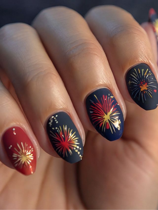A woman's nails with fireworks designs on them in vibrant fall colors.