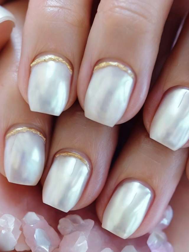 A woman's hands with white nails and gold trim.