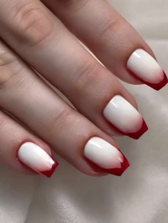 A woman's hand with red and white ombre nails.