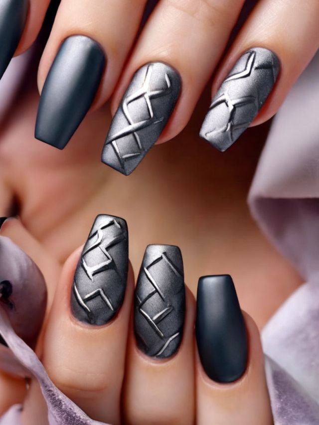 A woman is holding a pair of black and silver nails featuring elegant nail designs.