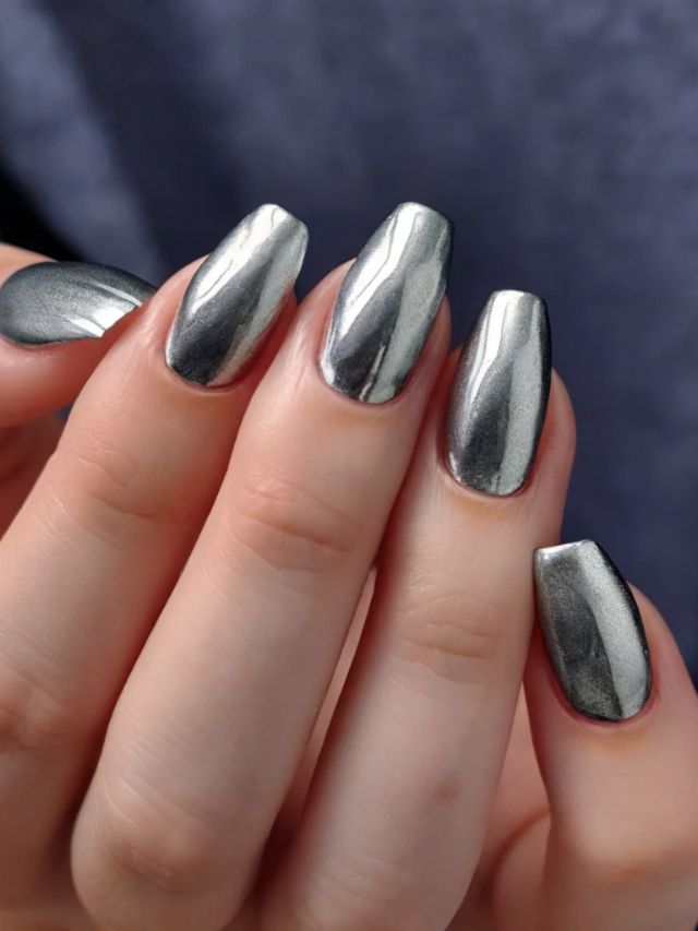 A woman's hands with silver nail polish on them.