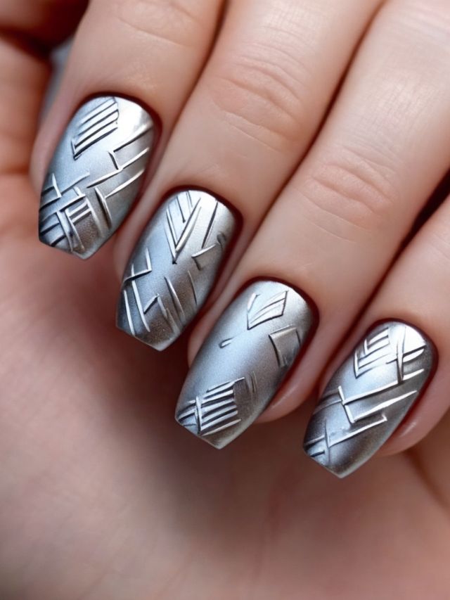 A woman holding a silver nail with geometric designs on it.