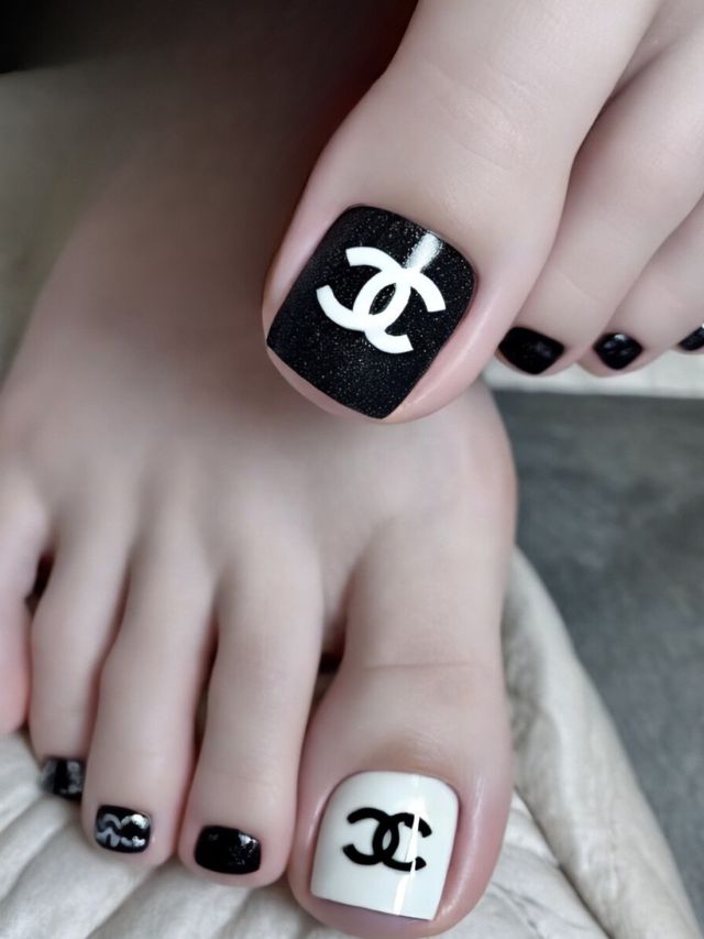 Black and white toe nails with chanel logo on them.