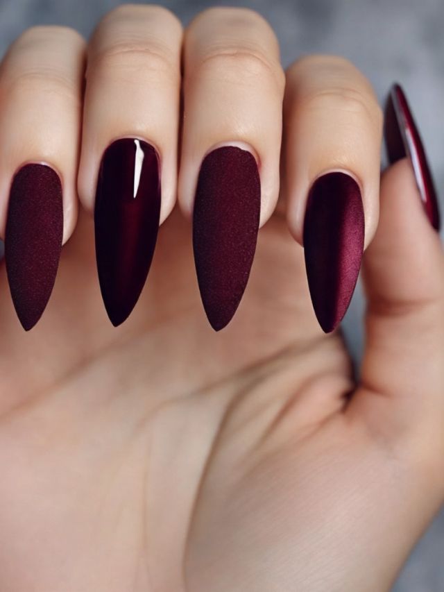 A woman's hand with burgundy stiletto nails featuring cute fall toe nail designs.