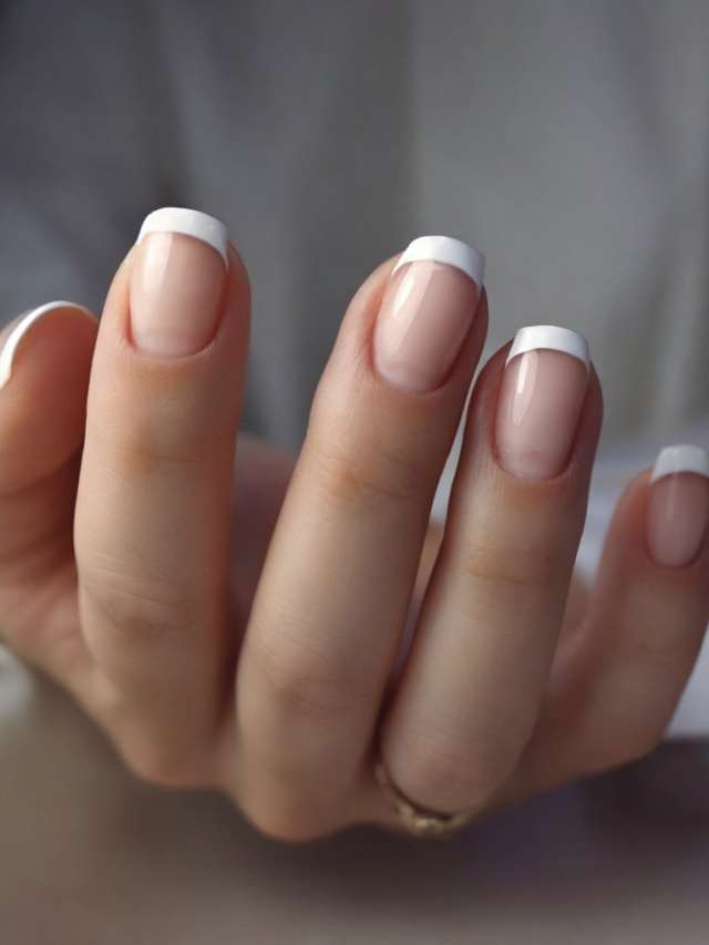 A woman's hands with french manicures on them.