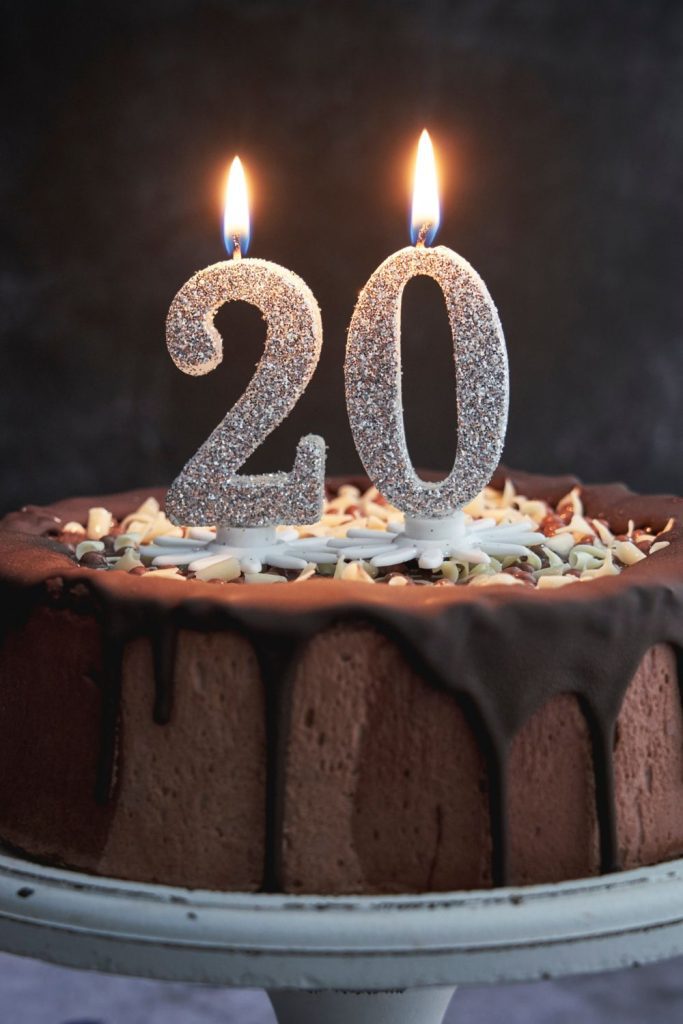 Chocolate cake with the number 20 candles lit on top, one of the best 20th birthday gift ideas.
